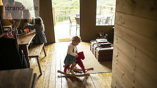 Nettes Mädchen spielt auf Schaukelpferd in Holzhütte