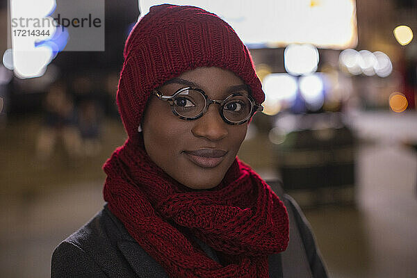 Porträt selbstbewusste junge Frau mit Brille Schal und Hut in der Nacht