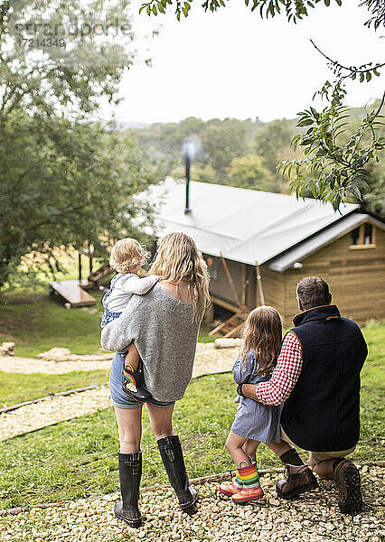 Eltern und Töchter blicken auf die Hütte von einem Pfad im Wald