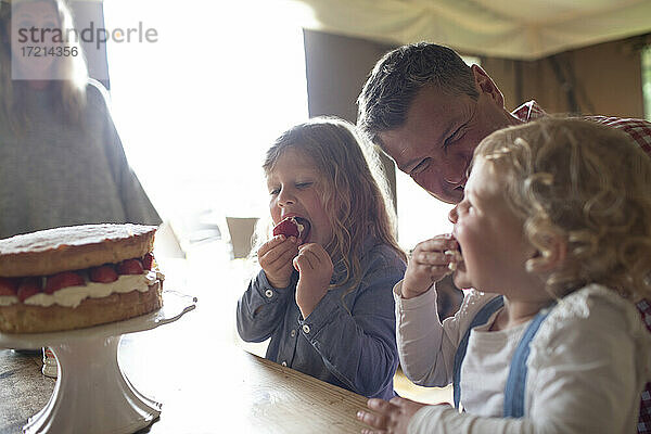 Glückliche Familie beim Genuss von Erdbeerkuchen