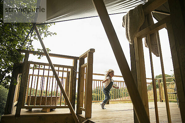 Unbekümmertes Mädchen läuft auf Holzkabine Balkon