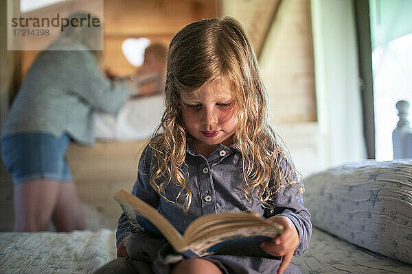 Nettes Mädchen liest Buch auf dem Bett