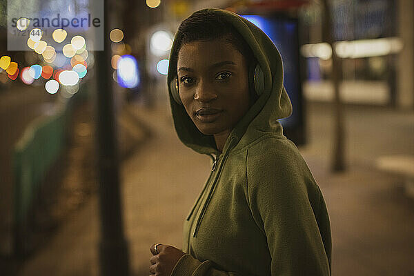 Porträt selbstbewusste junge Frau in Kapuze auf Stadt Bürgersteig in der Nacht