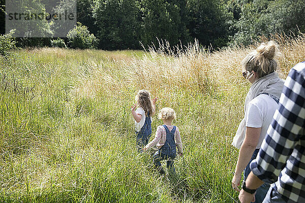 Eltern nach niedlichen Töchter in sonnigen ländlichen Sommer Feld