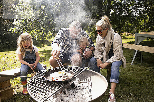 Glückliche Familie beim Frühstück auf dem Camping-Grill