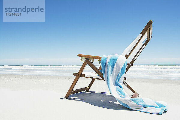 Leere Strandkorb mit gestreiften Handtuch am Strand