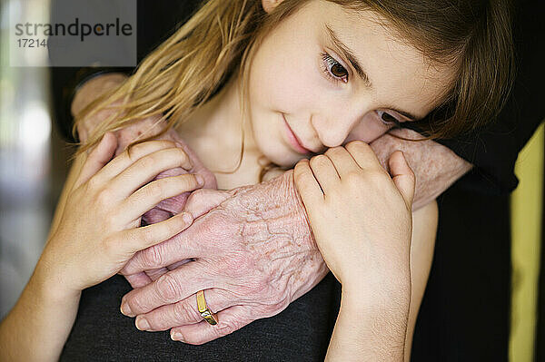 Nahaufnahme der Hand der Großmutter  die die Enkelin umarmt (8-9)