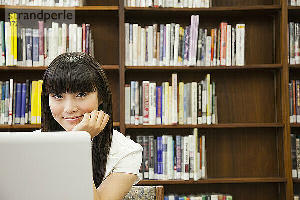 Asiatische Frau mit Laptop in der Bibliothek