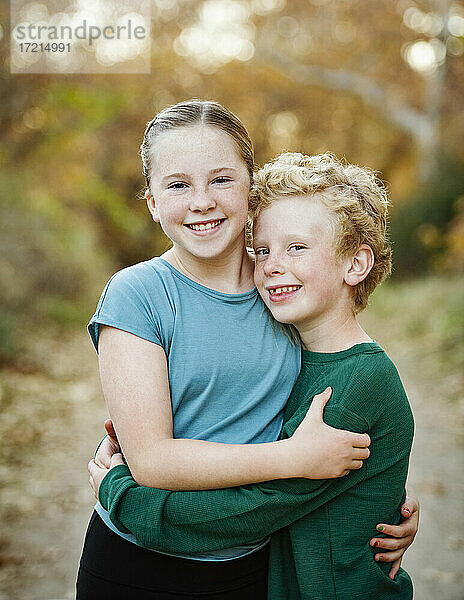 Vereinigte Staaten  Kalifornien  Mission Viejo  Portrait von lächelndem Bruder (10-11) und Schwester (12-13)  die sich im Wald umarmen