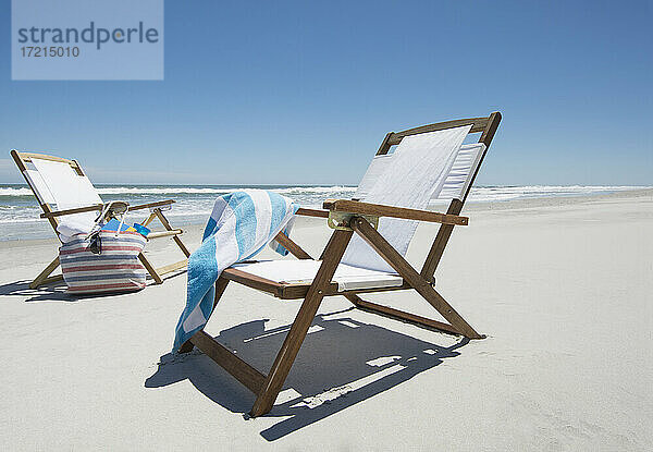 Leere Strandstühle mit Tasche und Handtuch am Strand