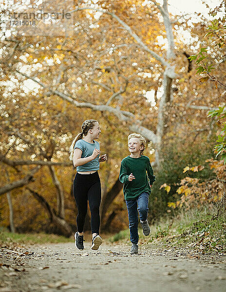 Vereinigte Staaten  Kalifornien  Mission Viejo  Junge (10-11) und Mädchen (12-13) laufen auf Fußweg im Wald