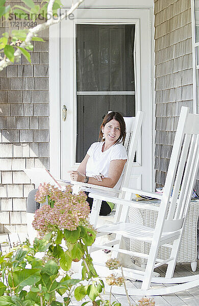 Vereinigte Staaten  Massachusetts  Nantucket  Porträt einer lächelnden Frau  die auf einer Veranda mit Laptop sitzt
