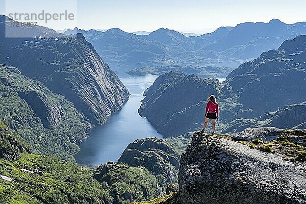 Wanderin  junge Frau steht auf Felsen und blickt in die Ferne  Fjord mit Bergen  Wanderung zur Trollfjord Hytta  am Trollfjord und Raftsund  Lofoten  Nordland  Norwegen  Europa