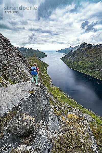 Fjord und Berge  Blick vom Berg Barden  junge Wanderin steht an einer Felsklippe  Senja  Norwegen  Europa