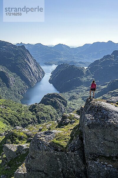 Wanderin  junge Frau steht auf Felsen und blickt in die Ferne  Fjord mit Bergen  Wanderung zur Trollfjord Hytta  am Trollfjord und Raftsund  Lofoten  Nordland  Norwegen  Europa