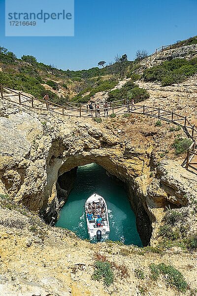 Ausflugsboot im türkisen Meer fährt durch Felshöhlen und Felsbögen  Steilküste aus Sandsteinfelsen  Algarve  Lagos  Portugal  Europa