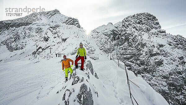 Zwei Skitourengeher am Gipfel des Osterfelderkopf im Schnee  hinten verschneite Alpspitze mit Sonnenstern  Wettersteingebirge  Garmisch-Partenkirchen  Bayern  Deutschland  Europa