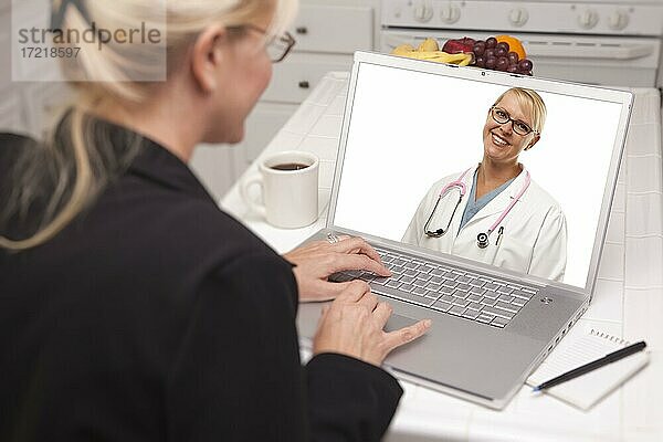 Frau in Küche mit Laptop  Online-Chat mit Krankenschwester oder Ärztin auf Bildschirm