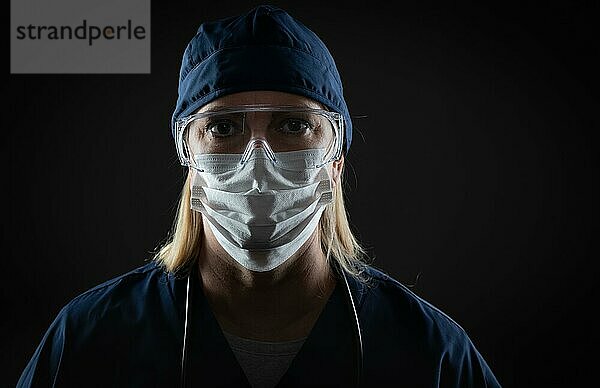 Frau  medizinisches Personal mit schützender Atemschutzmaske und Schutzbrille  vor dunklem Hintergrund