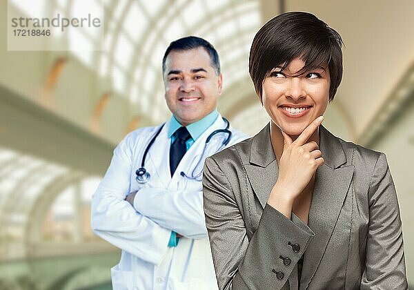 Glückliche multiethnische Frau schaut zur Seite  Arzt steht hinter ihr im Krankenhaus