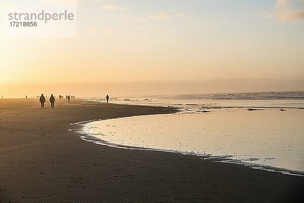 Menschen spazieren im Dunst bei Sonnenuntergang am Strand  Langeoog  Ostfriesische Inseln  Niedersachsen  Deutschland  Europa