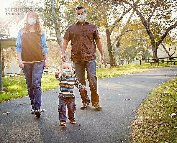 Glückliche multiethnische Familie im Park tragen medizinische Gesichtsmaske  USA  Nordamerika