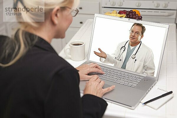 Frau in Küche mit Laptop  Online-Chat mit Arzt auf Bildschirm