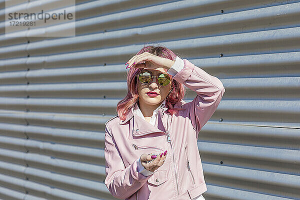 Junge Frau mit Sonnenbrille hält Konfetti an einem sonnigen Tag