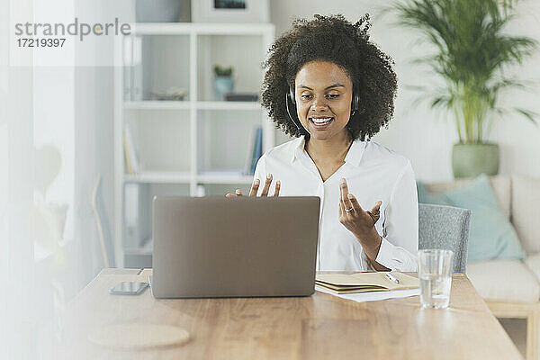 Frau mit Headset bei einem Videogespräch über einen Laptop zu Hause
