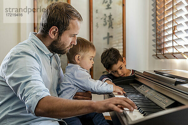 Vater unterrichtet seine Söhne zu Hause am Klavier