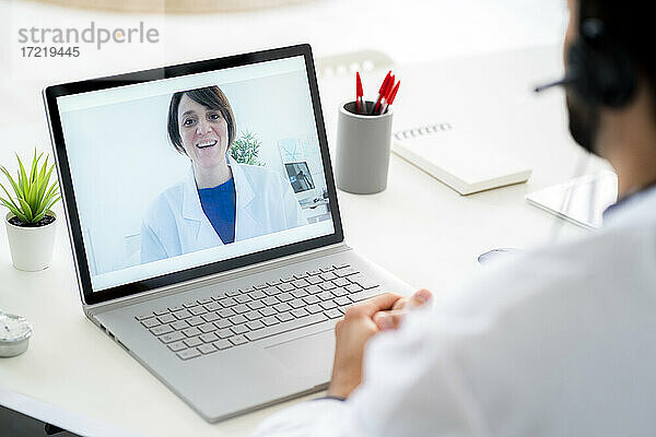 Männlicher Arzt bespricht sich mit einer Kollegin per Videokonferenz über einen Laptop