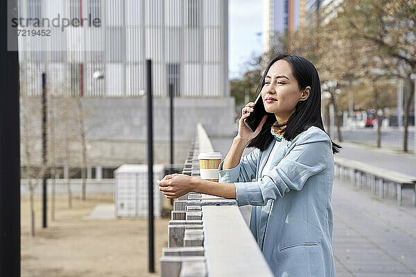 Geschäftsfrau schaut weg  während sie auf dem Gehweg mit dem Handy telefoniert