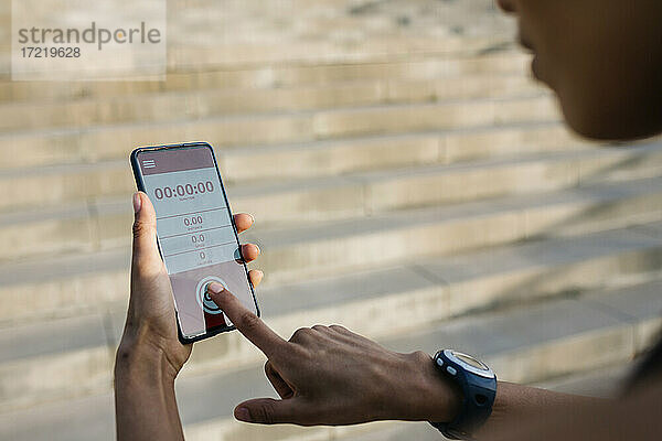 Sportlerin stellt Timer auf ihrem Smartphone ein