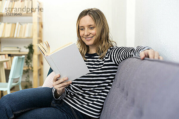 Mittlere erwachsene Frau liest zu Hause ein Buch