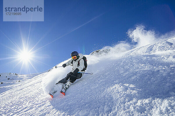 Die Sonne scheint über einem jungen Mann beim Skifahren im Arlberg-Massiv