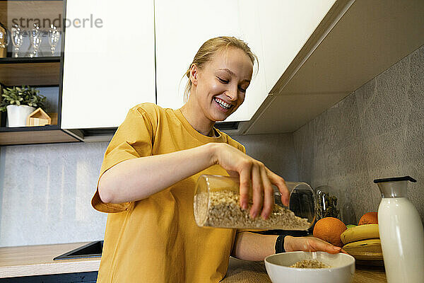 Lächelnde Frau gießt Essen in eine Schüssel in der Küche