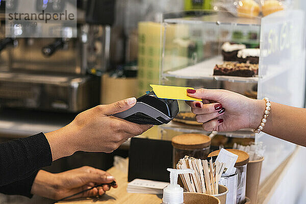 Frau bezahlt mit Kreditkarte in einem Café