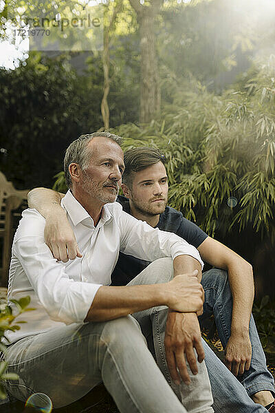 Nachdenklicher Vater und Sohn sitzen zusammen im Hinterhof