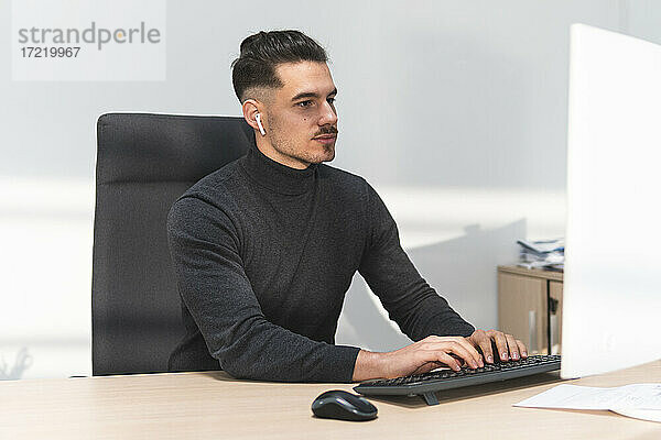 Junger Geschäftsmann arbeitet am Computer am Schreibtisch im Büro