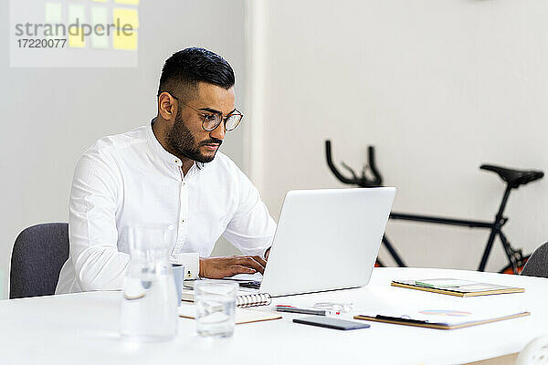 Männlicher Unternehmer mit Laptop auf dem Schreibtisch bei der Arbeit im Büro