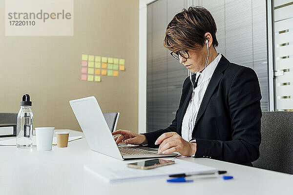 Weiblicher Geschäftsmann mit Laptop am Schreibtisch im Büro