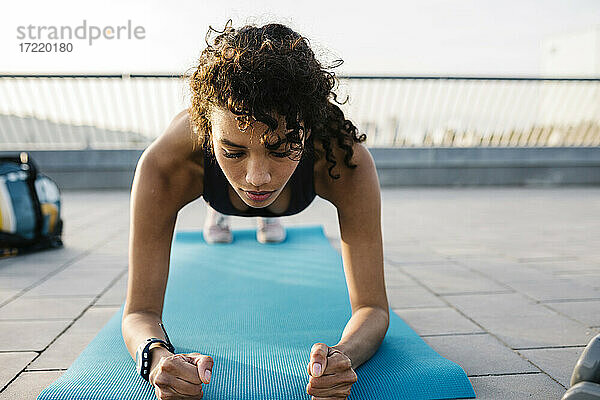 Weibliche Athletin beim Training in der Plank-Position auf einer Trainingsmatte