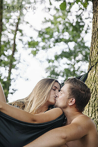 Paar entspannt sich in der Hängematte am See und küsst sich