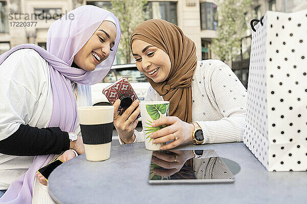Arabische Frauen mit Kaffeetasse und Smartphone in einem Straßencafé in der Stadt