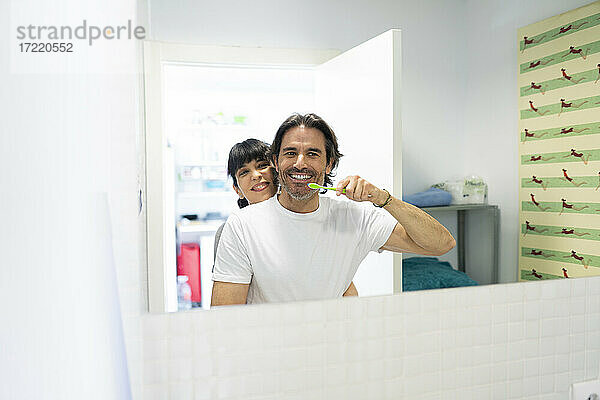 Frau umarmt Mann beim Zähneputzen im Badezimmer zu Hause