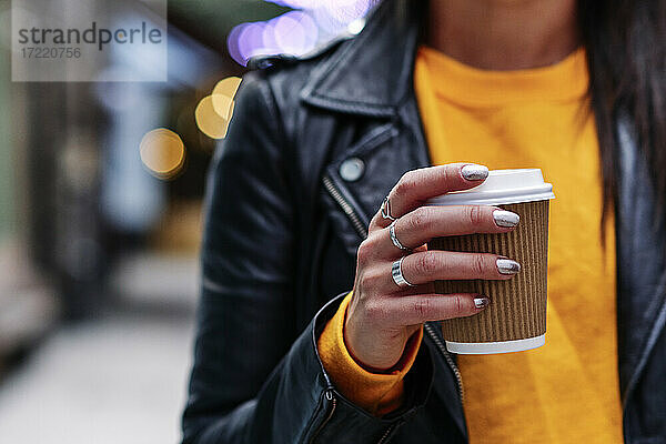 Frau mit Ringen hält Kaffeetasse in der Stadt