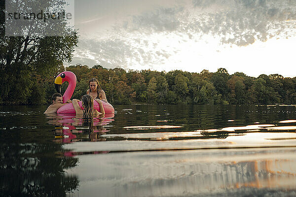 Freunde haben Spaß auf einem See auf einem schwimmenden rosa Flamingo-Reifen