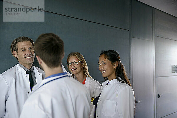 Lächelndes männliches und weibliches Gesundheitspersonal im Gespräch auf dem Korridor eines Krankenhauses