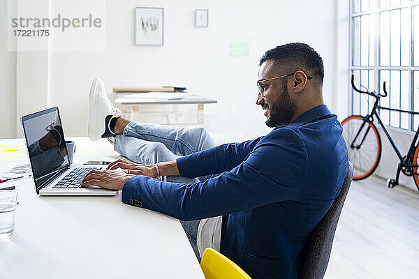Entspannter Geschäftsmann arbeitet am Laptop in einem modernen Büro
