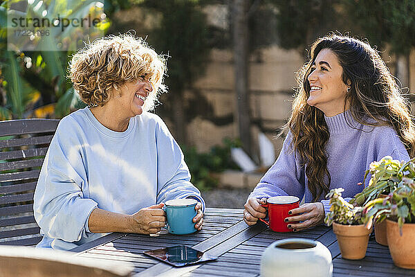 Fröhliche Mutter und Tochter beim Kaffee im Vorgarten